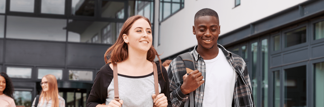 Smiling diverse students walking on a modern university campus.